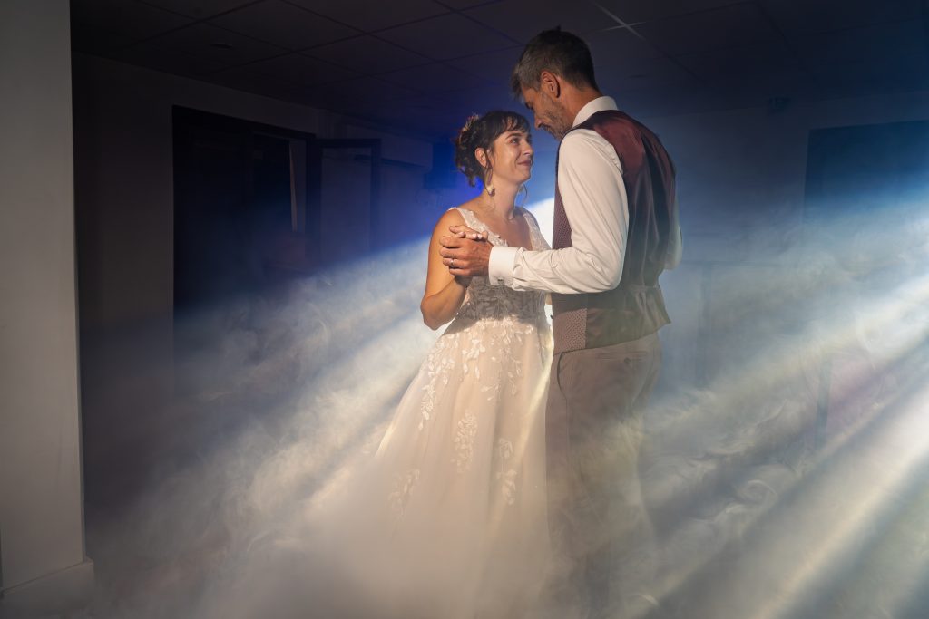 Photo en couleur d'un couple de mariés lors de la première danse avec de la fumée