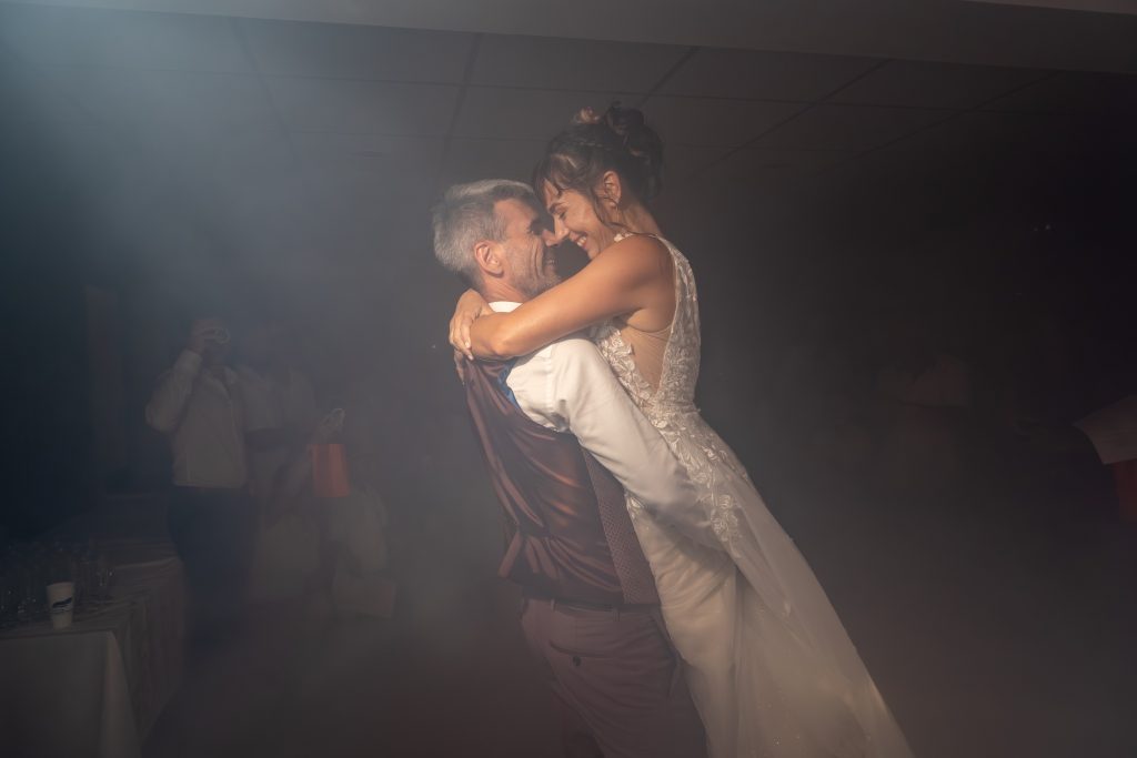 Photo en couleur d'un couple de mariés souriant lors de la première danse avec de la fumée